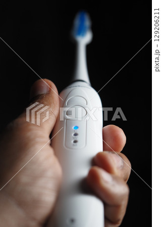 Electric toothbrush held by hand with focus on bristles 129206211
