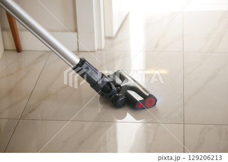 Vacuum cleaning on shiny tiled floor in bright room Vacuum cleaning on shiny tiled floor in bright room 129206213