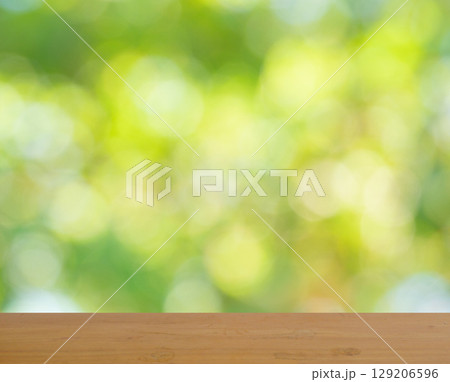 Empty brown wooden table surface for product placement with bokeh from green leaves bush in background, Leaf blurred into circle 129206596