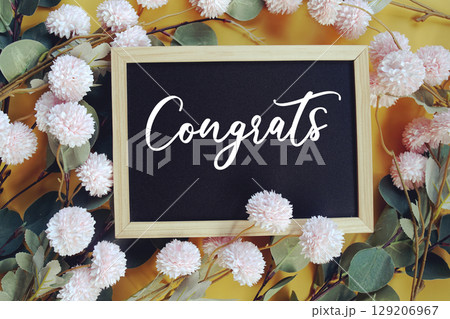 Congrats text with flowers decoration on yellow background 129206967