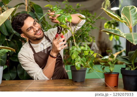 Young man working in the flower shop and looking involved Young man working in the flower shop and looking involved 129207033
