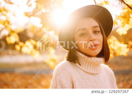 Sunny lifestyle portrait of young stylish woman walking on park, wearing cute trendy hat. Fashion concept. 129207167