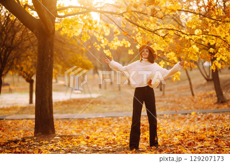 Stylish woman enjoying autumn weather in the park. Fashion, style concept. Stylish woman enjoying autumn weather in the park. Fashion, style concept. 129207173