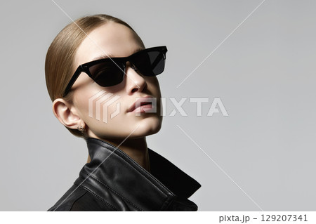 pretty blond girl in black glasses and leather coat 129207341