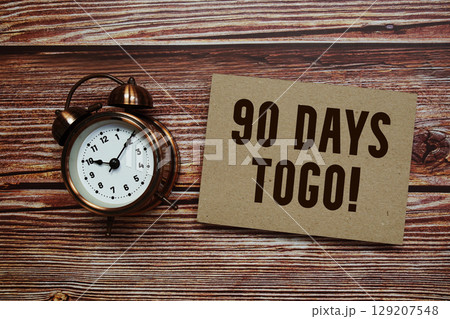 90 Days To Go! text with alarm clock on wooden background 129207548