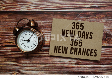 365 New Days New Chances text with alarm clock on wooden background 129207550