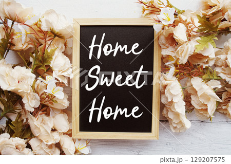 Home Sweet Home text with flower decoration on wooden background 129207575