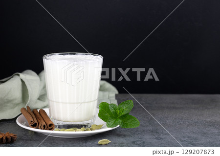 Popular Indian cold drink - Lassi. Yoghurt drink with spices, mint on black background. Indian food Popular Indian cold drink - Lassi. Yoghurt drink with spices, mint on black background. Indian food 129207873