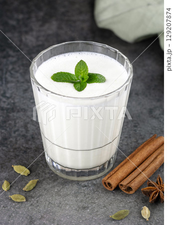 Traditional Indian yogurt drink with spices lassi: cardamom, cinnamon stick, mint on gray background Traditional Indian yogurt drink with spices lassi: cardamom, cinnamon stick, mint on gray background 129207874