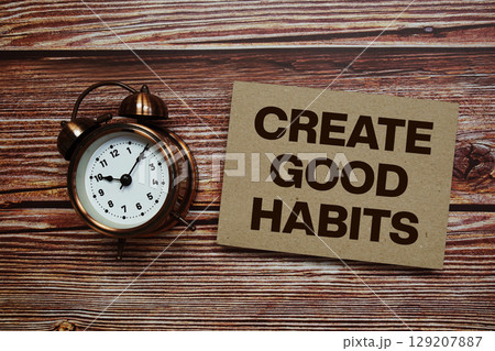 Create Good Habits text with alarm clock on wooden background Create Good Habits text with alarm clock on wooden background 129207887
