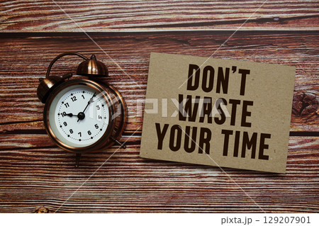 Don't Waste Your Time text with alarm clock on wooden background Don't Waste Your Time text with alarm clock on wooden background 129207901