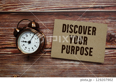 Discover Your Purpose text with alarm clock on wooden background 129207902