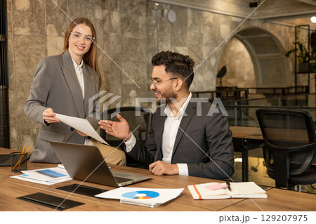 Colleagues working together in the office and discussing the project details 129207975