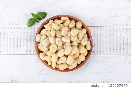 Raw Italian pasta potato gnocchi and basil on white background. Top view. Raw Italian pasta potato gnocchi and basil on white background. Top view. 129207979