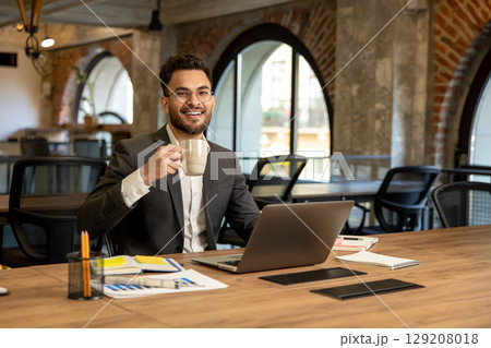 Young caucasian man sitting in the office and having coffee 129208018