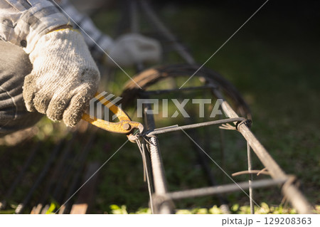 worker uses steel tying wire to fasten steel rods to reinforcement bars. 129208363
