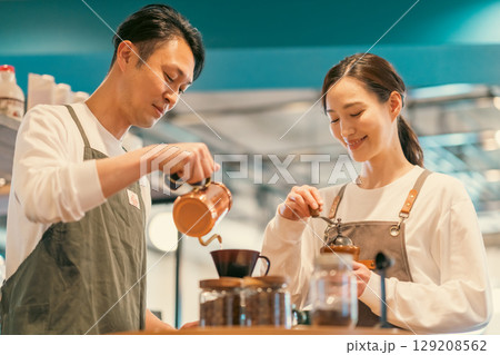 ドリップケトルでコーヒーを淹れる店員とグランドする店員 129208562