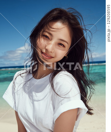 白いTシャツの女性と夏の海｜笑顔が映える爽やかなビーチポートレート 129208595