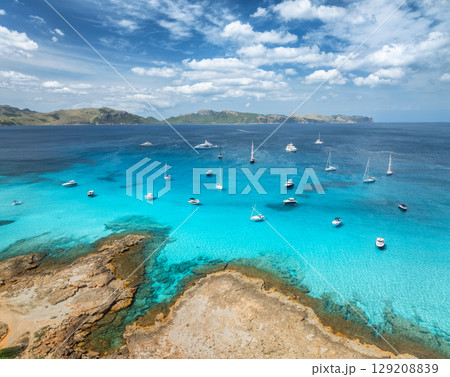 Aerial view of yachts and sailboats anchored in turquoise sea Aerial view of yachts and sailboats anchored in turquoise sea 129208839