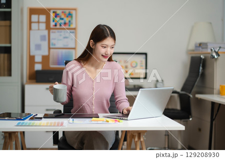 Female coder or developer working using a computer display and smartphone in problem solving at workplace. 129208930