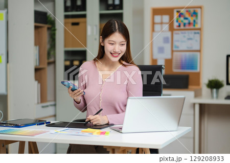 Female coder or developer working using a computer display and smartphone in problem solving at workplace. 129208933