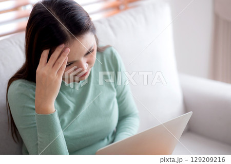 Young asian businesswoman working laptop with stress and frustrated in living room at home. 129209216
