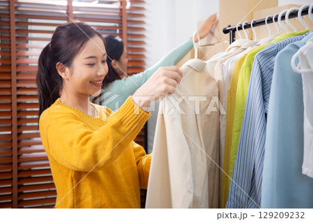 Two young asian woman arranging clothes in store for preparation delivery, seller choice clothes. Two young asian woman arranging clothes in store for preparation delivery, seller choice clothes. 129209232