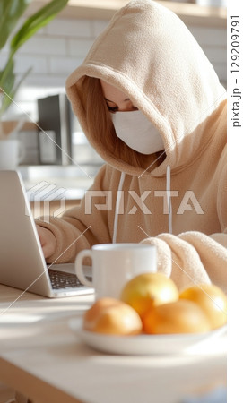 Young remote tech worker in oversized hoodie works from bright kitchen island with data science dashboard open. Data scientist 129209791