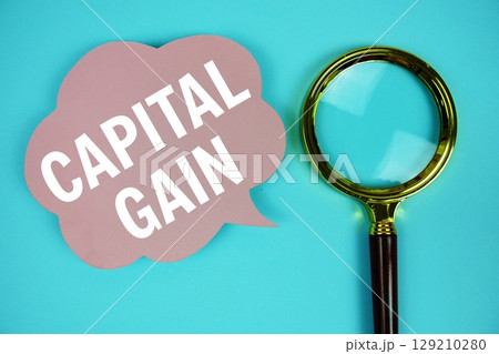 Capital Gain text with speech bubble and magnifying glass on blue background Capital Gain text with speech bubble and magnifying glass on blue background 129210280