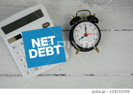 Net Debt text with calculator and alarm clock  on wooden background 129210309