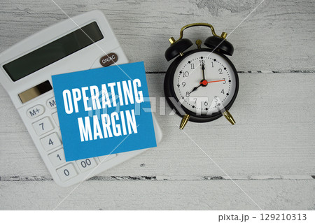Operating Margin text with calculator and alarm clock  on wooden background 129210313