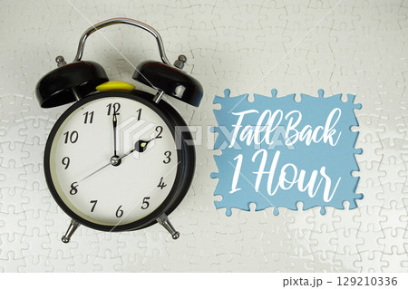 Fall Back 1 Hour text with alarm clock on blue background Fall Back 1 Hour text with alarm clock on blue background 129210336