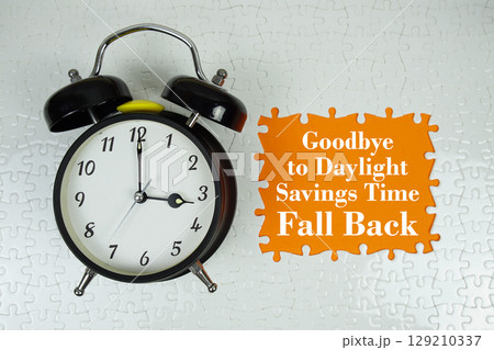 Goodbye to Daylight Savings Time Fall back text with alarm clock on orange background 129210337