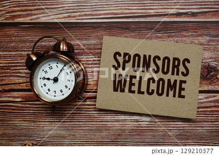 Sponsors Welcome text with alarm clock on wooden background Sponsors Welcome text with alarm clock on wooden background 129210377