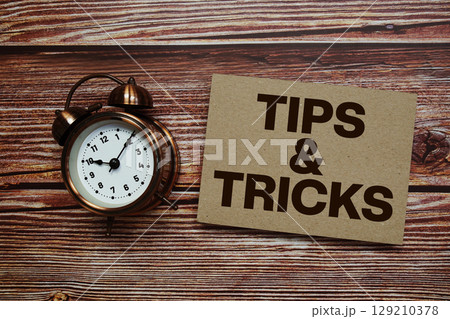 Tips And Tricks text with alarm clock on wooden background Tips And Tricks text with alarm clock on wooden background 129210378