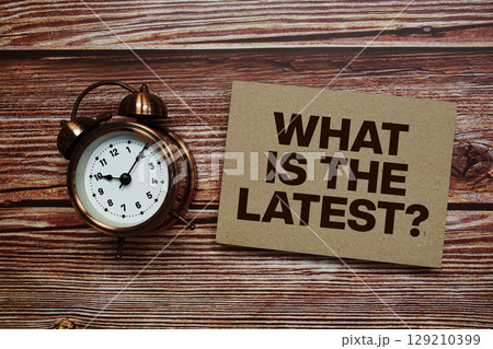 What Is The Latest? text with alarm clock on wooden background What Is The Latest? text with alarm clock on wooden background 129210399