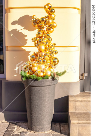 Artificial Christmas tree made entirely of golden baubles in pot. Funny xmas from shiny gold balls in flowerpot Artificial Christmas tree made entirely of golden baubles in pot. Funny xmas from shiny gold balls in flowerpot 129210844