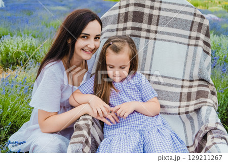A beautiful little daughter in a beautiful purple dress sits in a rocking chair A beautiful little daughter in a beautiful purple dress sits in a rocking chair 129211267