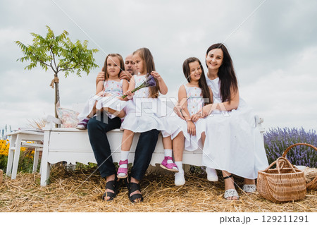 A white retro bench stands in the lavender field, where a happy family has gathered 129211291