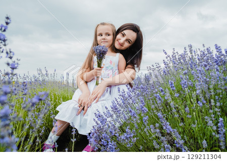 The mother gently embraces her daughter against the backdrop of the lavender field The mother gently embraces her daughter against the backdrop of the lavender field 129211304