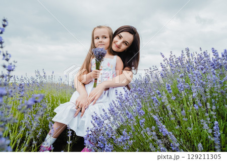 The mother gently embraces her daughter against the backdrop of the lavender field The mother gently embraces her daughter against the backdrop of the lavender field 129211305