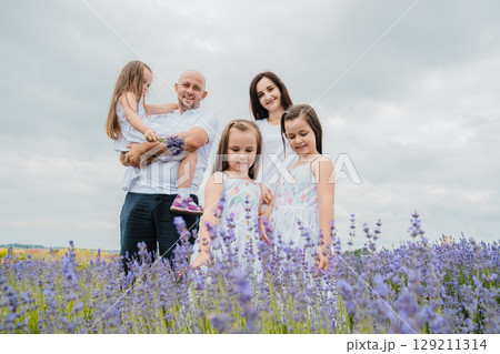 The mother and her daughters, dressed in white dresses, stand in the purple lavender field 129211314