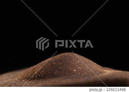 Gold sparkly hourglass sand on black background. Minimalist low key poto for concepts of time, travel to the desert Gold sparkly hourglass sand on black background. Minimalist low key poto for concepts of time, travel to the desert 129211406