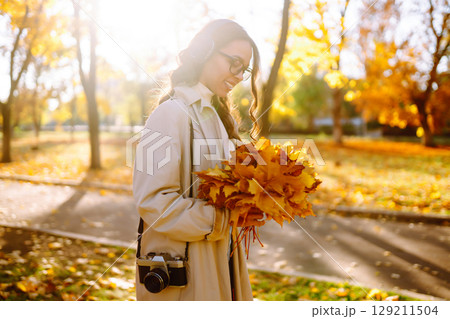 Woman taking pictures in autumn forest. Smiling woman enjoying autumn weather. Lifestyle concept. 129211504