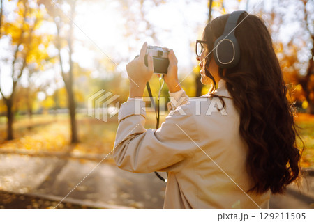 Woman taking pictures in autumn forest. Smiling woman enjoying autumn weather. Lifestyle concept. 129211505