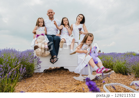 The father and daughters are comfortably seated on an old white chest The father and daughters are comfortably seated on an old white chest 129211532