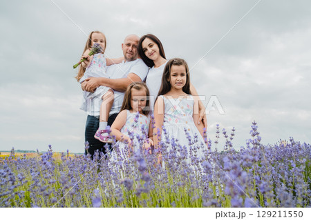 A mother in a white dress is hugging her husband, who is holding a cute little girl A mother in a white dress is hugging her husband, who is holding a cute little girl 129211550