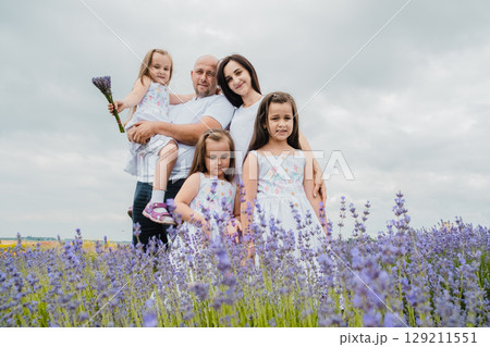 A young mother looks tenderly at her beautiful daughters in a field of lavender 129211551