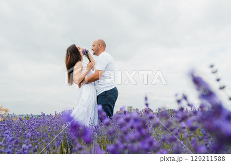 A young couple in love stands listening to the silence of the lavender field and the beating of their hearts A young couple in love stands listening to the silence of the lavender field and the beating of their hearts 129211588