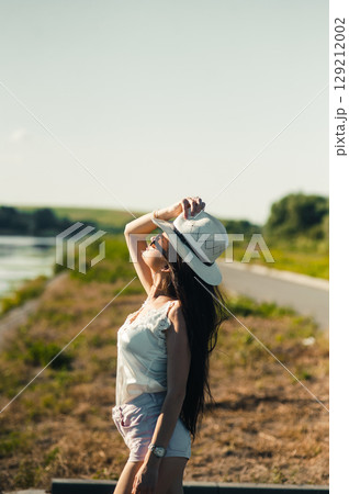 A beautiful girl is basking in the sun by the lake A beautiful girl is basking in the sun by the lake 129212002